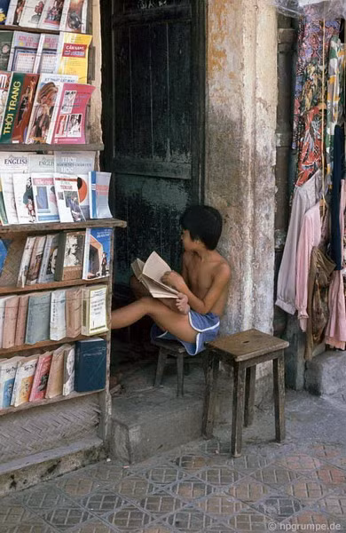 Cậu bé này tranh thủ đọc một cuốn sách dày cộp khi ngồi trông cửa hàng sách cũ.