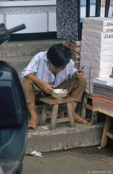 Một cậu bé ăn trưa bên quầy bán giấy.