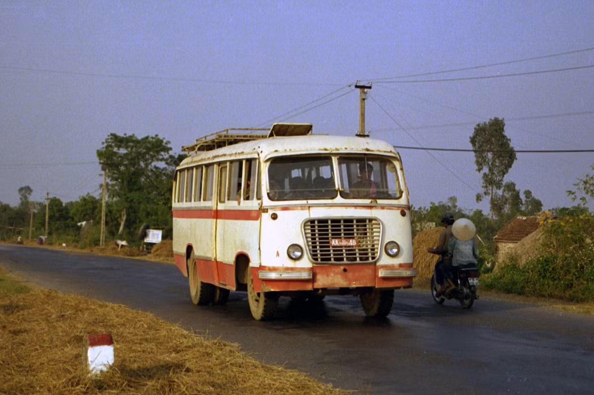 Một chiếc xe buýt quân đội mang biển số AA-11-48 chạy trên con đường ngoại ô Hà Nội.