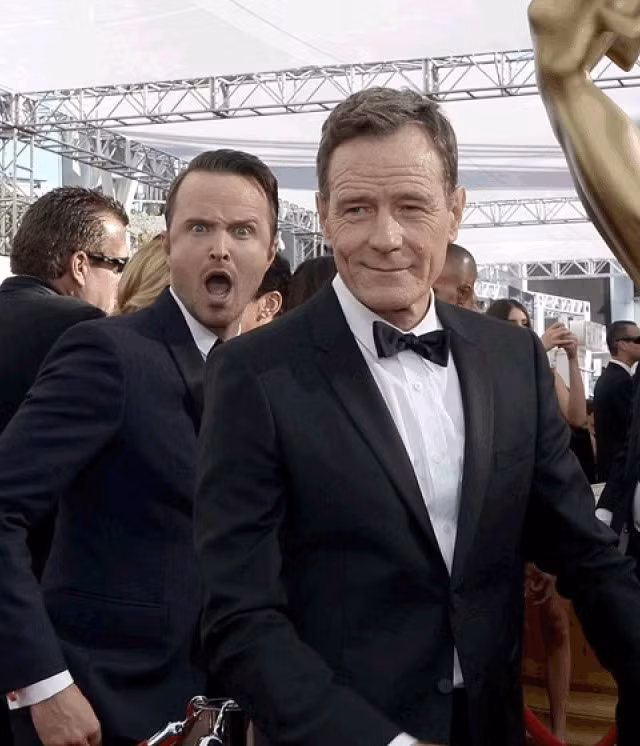 Aaron Paul ra chiều hốt hoảng sau lưng Bryan Cranston khi ông đang cười duyên chụp ảnh.