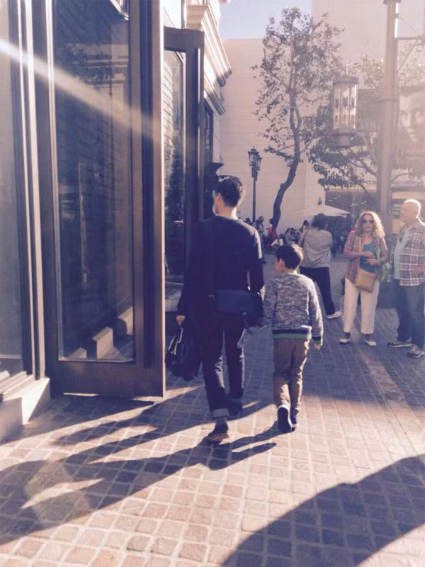 Hai bố con dắt tay nhau trên phố trên đường shopping.