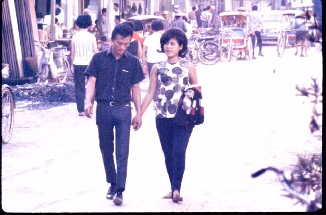 Cặp đôi tay trong tay đi trên con phố sầm uất.