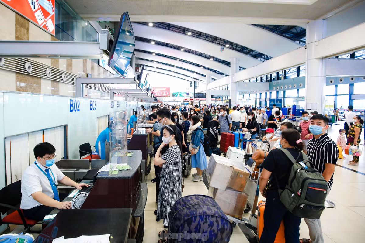 Những chuyến bay dày đặc trên bảng thông báo tại sảnh nội địa T1 với lượng hành khách xếp hàng kéo dài đợi làm thủ tục check-in.