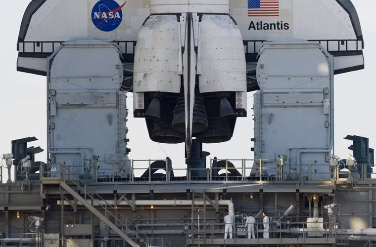 Nhân viên NASA đang đứng trên bệ phóng di động dưới tàu Atlantis.