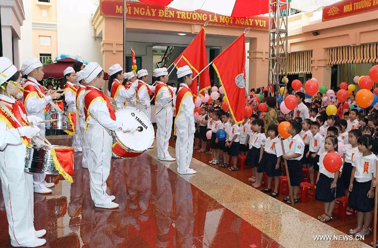 Các bé "heo vàng" háo hức và chăm chú theo dõi đội nghi thức của nhà trường trình diễn trong lễ khai giảng ở trường tiểu học Trần Quốc Toản, Hà Nội, Việt Nam.