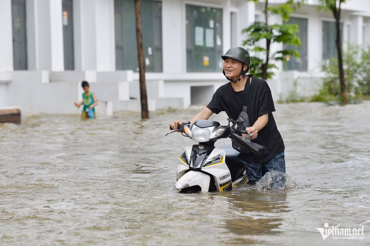 Toàn bộ khu vực này bị tê liệt, người dân đi lại rất khổ sở. Một thanh niên buộc phải dắt xe máy qua đoạn ngập.