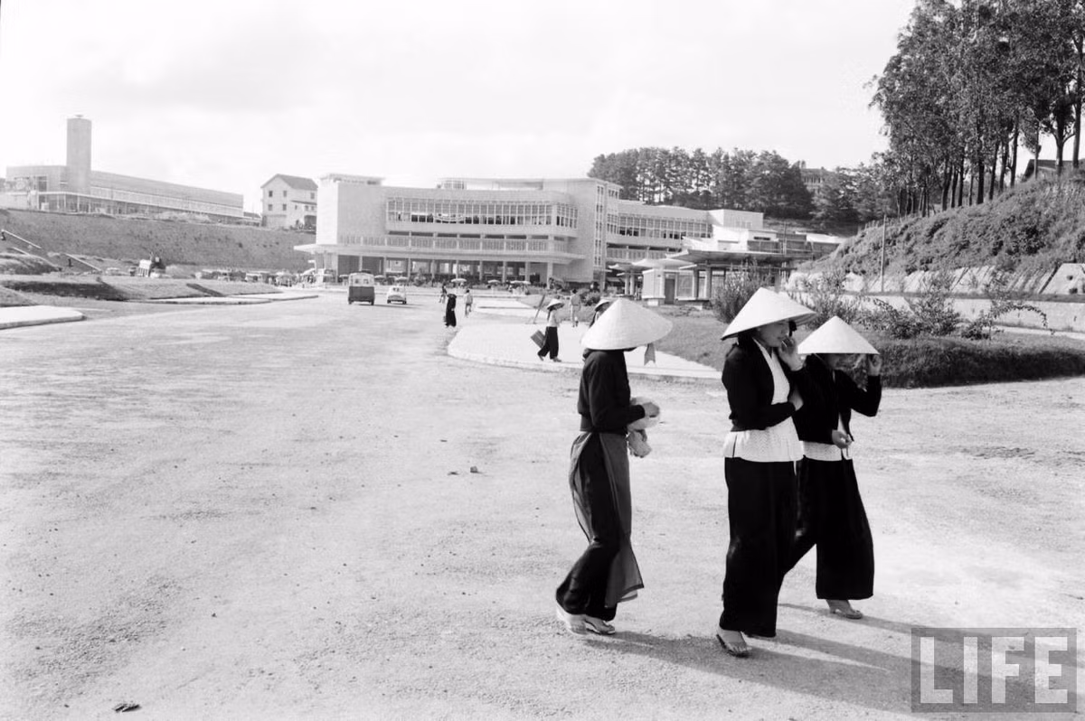 Những người phụ nữ đi ngang qua khu vực phía trước chợ Đà Lạt mới, Đà Lạt năm 1961. Góc trái phía trên bức ảnh là hội trường Hòa Bình, chính là chợ Đà Lạt cũ, nay là Rạp 3 Tháng 4. Ảnh: John Dominis / Life.
