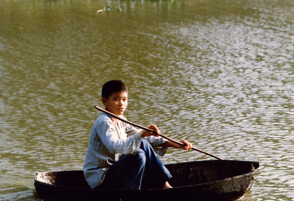 Cậu bé chèo thuyền thúng trên hồ.