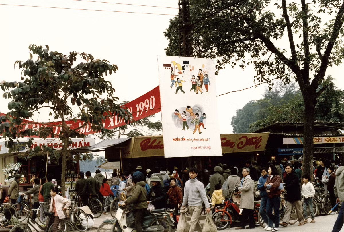Khu chợ Tết ở Hà Nội dịp giáp Tết Canh Ngọ 1990. Tấm áp-phích treo giữa phố có nội dung "Nghiêm cấm ném pháo bừa bãi".