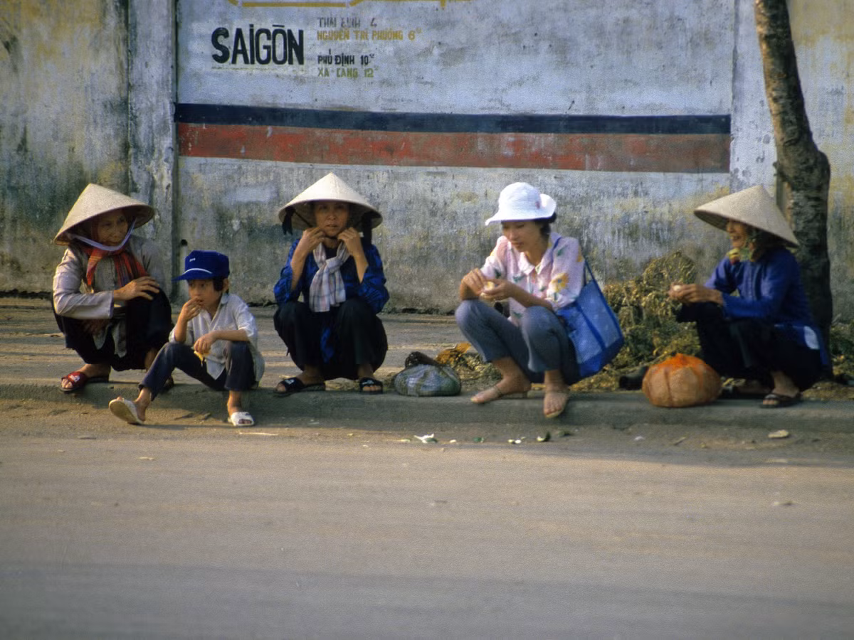 Phụ nữ và trẻ em ngồi trên vỉa hè.