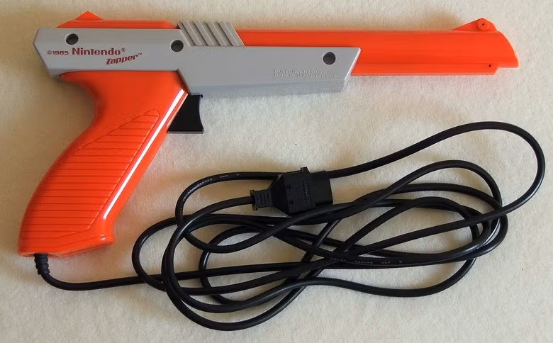 Đây là khẩu súng NES Zapper, niềm mơ ước của những đứa trẻ nghiền điện tử 4 nút ở Việt Nam, bởi không dễ gì tìm mua được thiết bị này. Cách sử sụng NES Zapper khá đơn giản, cứ nhằm vào màn hình TV mà... bắn.