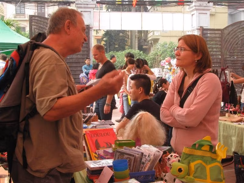 Một vị khách nước ngoài trao đổi với người bán hàng để tìm mua được thứ mong muốn.