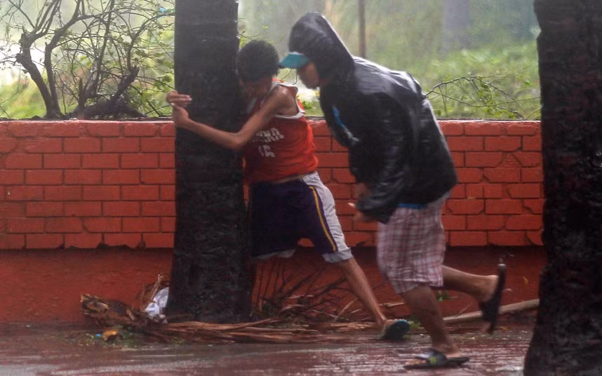 Nam thanh niên phải ôm gốc cây để tránh bị gió bão thổi bay ở thủ đô Manila.