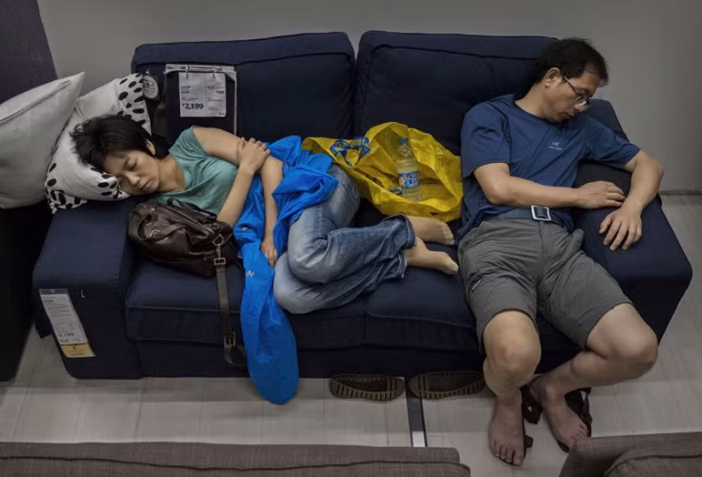 Một cặp vợ chồng tranh thủ ngủ trên ghế sofa tại cửa hàng Ikea.