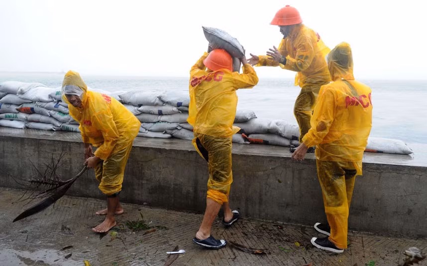 Công nhân dùng các bao tải cát để gia cố đê Roxas Boulevard.