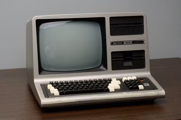  5. Tandy TRS-80 Model I. Cùng thời điểm ra đời với chiếc Apple II là Tandy TRS-80 Model I của Radio Shack. Một trong những yếu tố tạo ra sự thành công của dòng máy này đó là nó cung cấp cho người dùng một hệ thống phần mềm đa dạng. Trong vòng 2 năm vào khoảng cuối những năm 70 của thế kỉ trước thuộc thời kì thăng hoa đỉnh điểm của PC, TRS-80 là thiết bị được tiêu thụ mạnh nhất trên thị trường. Nếu điều này không xảy ra, có lẽ Apple hay Commodore đã là người chiến thắng những trận chiến đầu tiên ở thị trường đầy mới mẻ này.