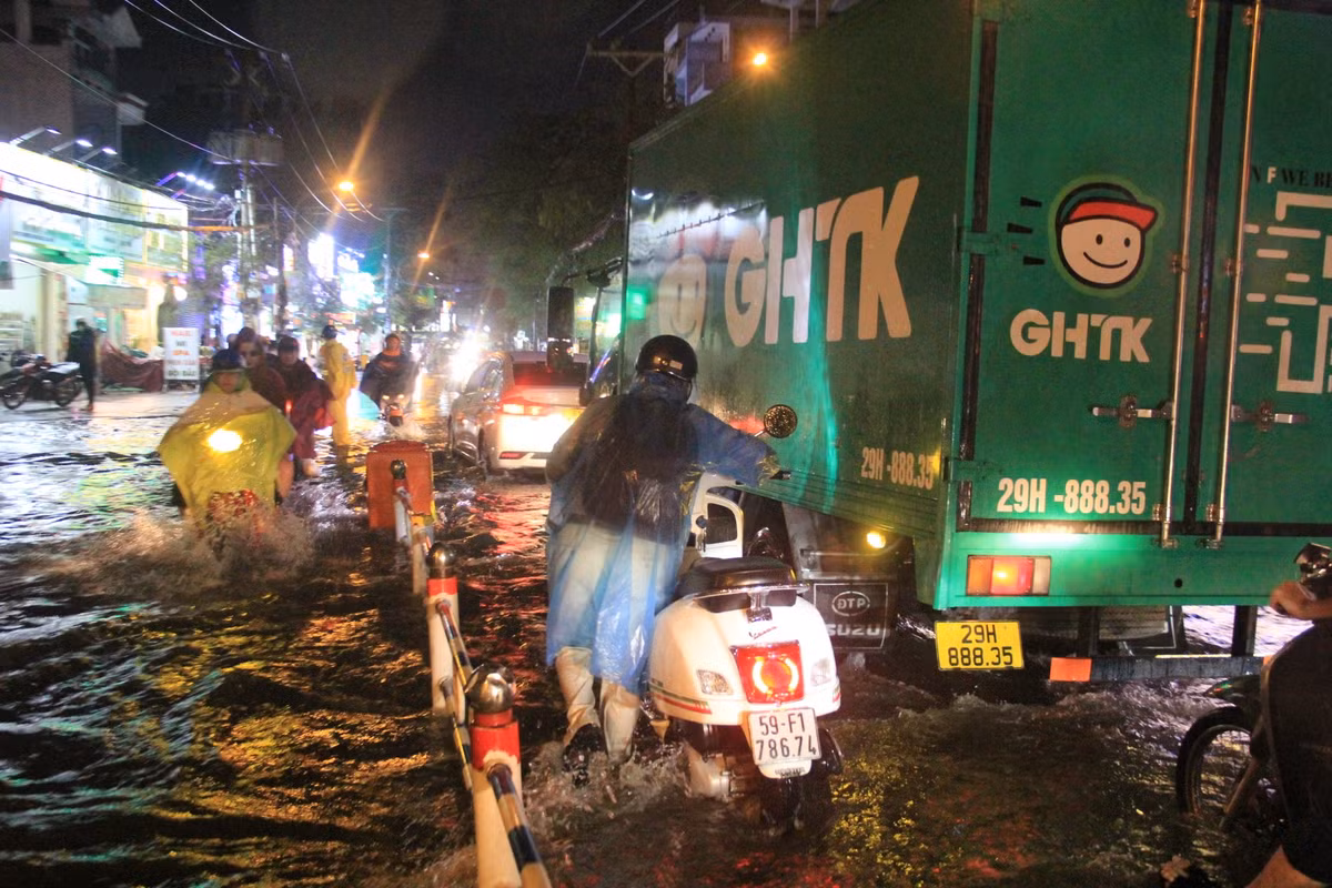 Người dân phải bì bõm lội nước đưa phương tiện thoát khỏi điểm ngập.