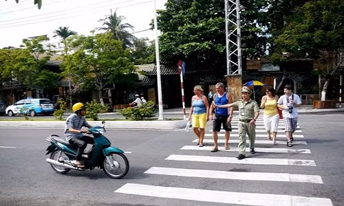 Đội viên Trịnh Nhật Minh Tú đưa khách qua đường Trần Phú. Ảnh: Trần Công .