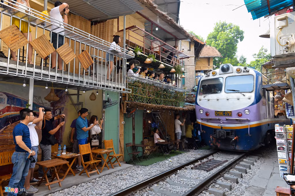 Du khách đứng gọn vào hai bên đường, lấy điện thoại, máy ảnh để ghi lại khoảnh khắc tàu đi qua. Một chủ quán cho biết khu vực này chưa xảy ra sự cố đáng tiếc nào.