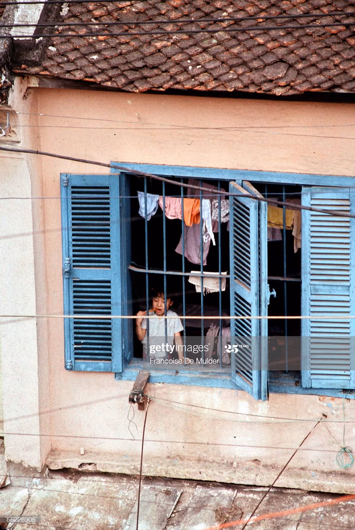 Em bé Hà Nội đánh răng bên cửa sổ.