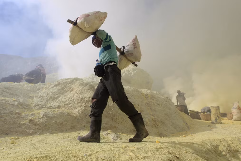 Một thợ mỏ giánh lưu huỳnh từ vừa khai thác được xuống khỏi ngọn núi lửa Kawah Ijen cao 2.600 m.
