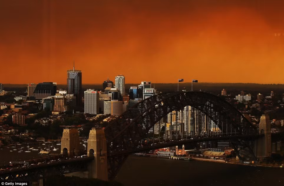 Bầu trời phía trên cầu cảng Sydney bị nhuộm một màu đỏ rực bởi những đám khói khổng lồ đến từ các đám cháy rừng dữ dội ở ngoại ô phía tây Sydney bao gồm Springwood, Winmalee và Lithgow.