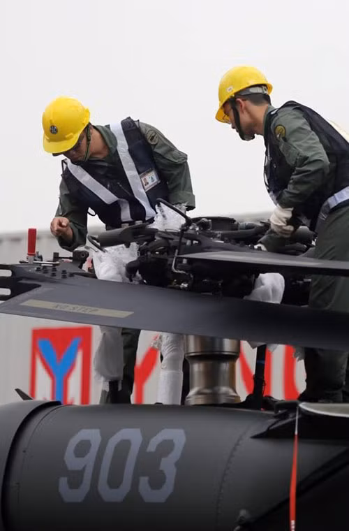 Các nhân viên đang tiến hành dỡ và lắp ráp bộ phận cánh của trực thăng UH-60 Black Hawk tại cảng Cao Hùng.