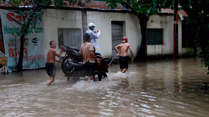 Thuê chở cả người và xe qua đoạn đường nước ngập sâu, tranh thủ ghi lại... khoảnh khắc đáng nhớ. Ảnh: Tuổi Trẻ