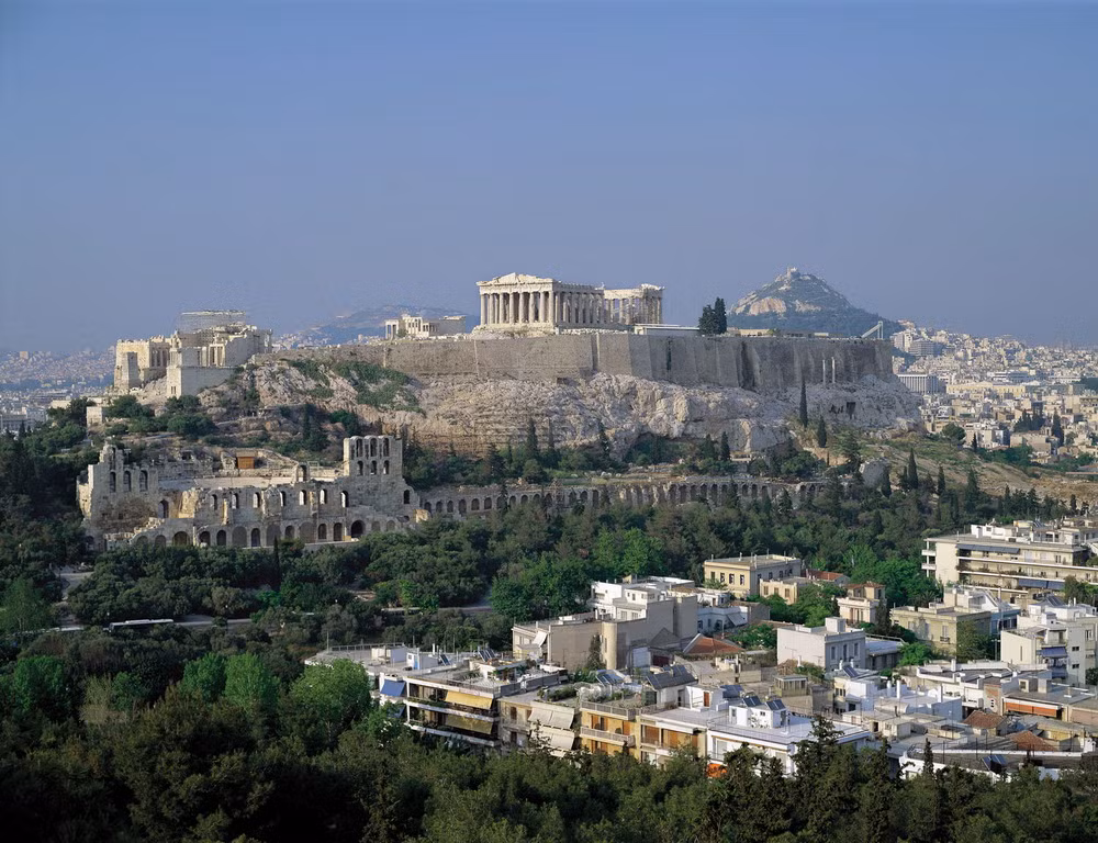Về mặt lịch sử, năm 490 TCN, người Athens đã đặt những tảng đá đầu tiên làm nền móng thành Acropolis để tôn thờ vị thần hộ mệnh của thành phố - nữ thần Athena Parthenos. Nhưng 10 năm sau, công trình này đã bị người Ba Tư phá hủy. Sau 30 năm tạm ngừng, nhà lãnh đạo Pericles đã cho xây dựng lại Acropolis với quy mô hoành tráng gấp nhiều lần.