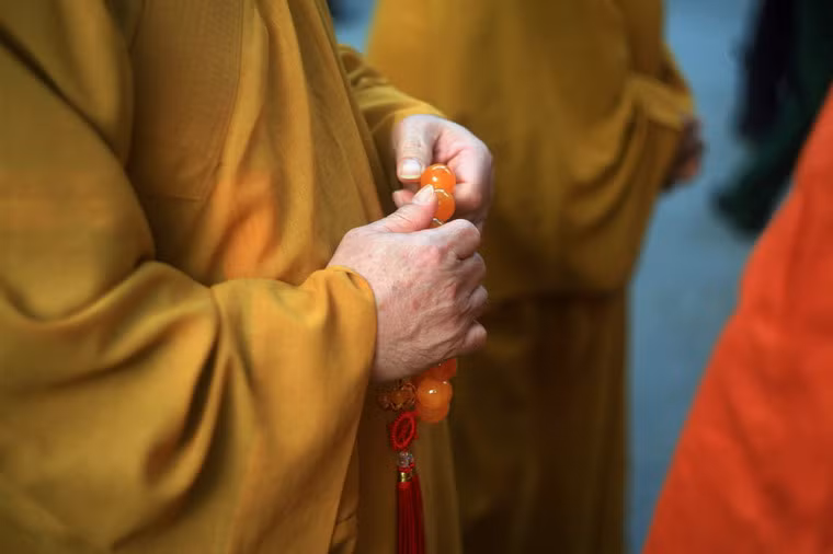 Một nhà tu hành trầm tư lần tràng hạt khi xếp hàng vào viếng Đại tướng.
