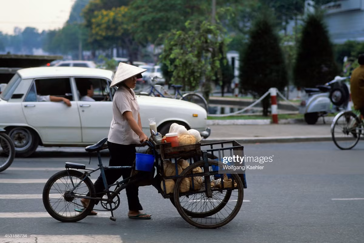 Người bán nước dừa dạo đi qua vòng xoay Cây Liễu, ngã tư Lê Lợi - Nguyễn Huệ.