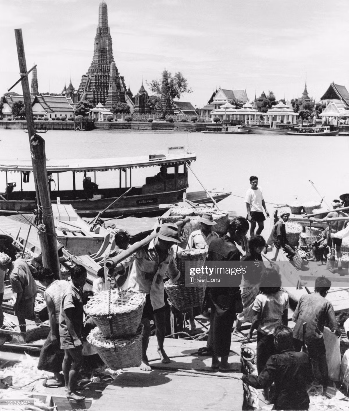 Cảnh bốc dỡ hàng hóa tại bền thuyền trên sông Chao Phraya. Bên kia sông là chùa Wat Arun.