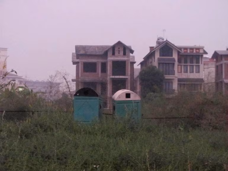 Hai nhà vệ sinh công cộng từ khi khởi công đến nay nằm lăn lóc ở góc mảnh đất.
