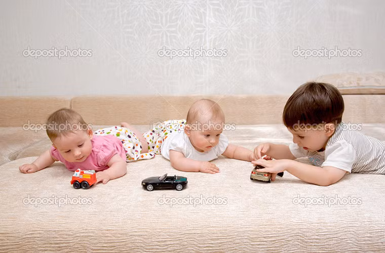 Hai bé gái sinh đôi đáng yêu chơi cùng anh cả một cách say mê.