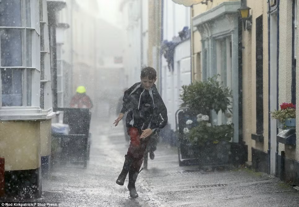 Một cậu bé ở Appledore, North Devon đội đầu trần chạy trong cơn mưa lớn tránh bão.