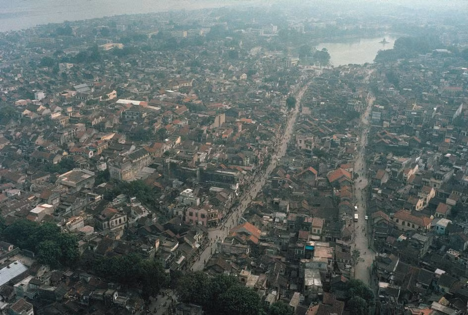 Trung tâm Hà Nội năm 1989 nhìn từ trên cao, với hồ Hoàn Kiếm ở góc trên bên phải. Bên trái là đường Hàng Ngang – Hàng Đào, bên phải là Lương Văn Can. Giai đoạn này quanh hồ chưa có bóng dáng các tòa nhà cao tầng. Ảnh: David Alan Harvey.