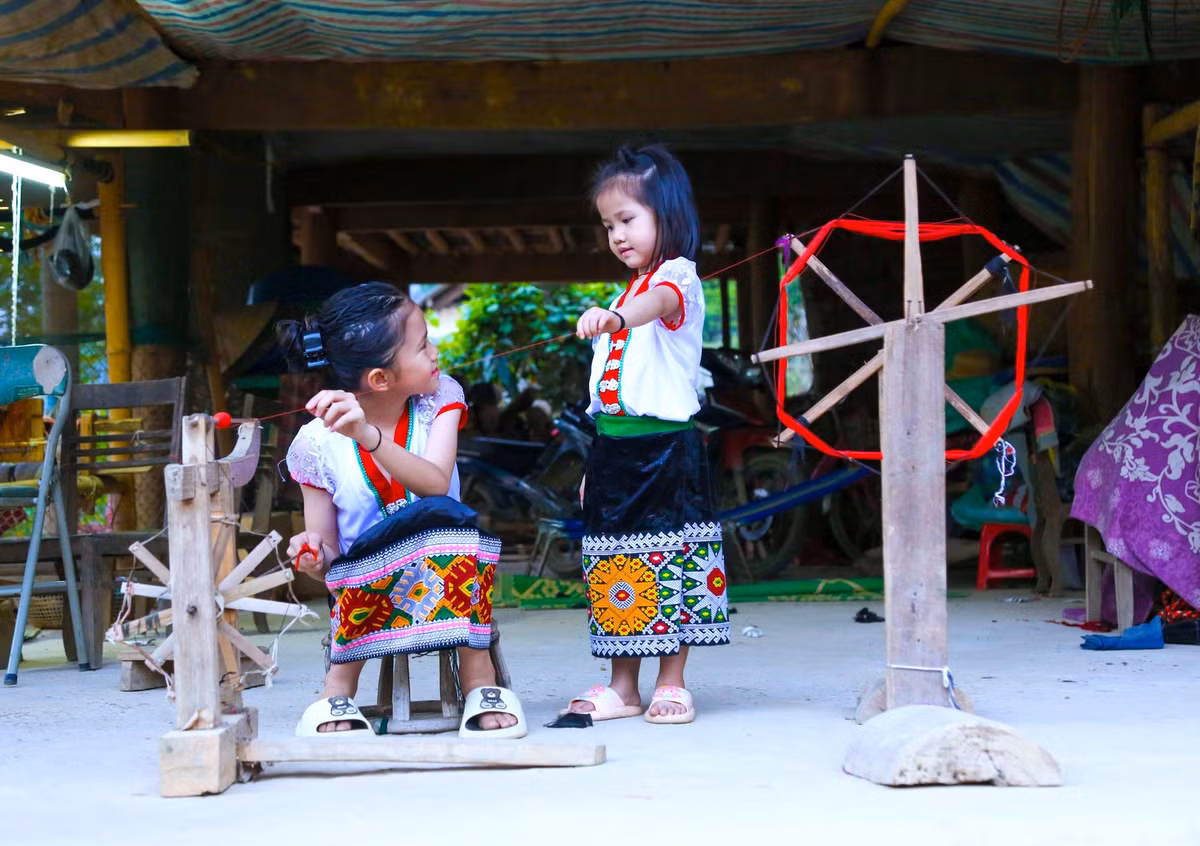 Tranh thủ những ngày được nghỉ học, hai chị em Lô Thị Yến Hương (trái) và Lô Thị Yến Vy ở bản Na, xã Hữu Lập (Kỳ Sơn) được học kỹ năng cuộn chỉ, dệt vải, thêu váy.
