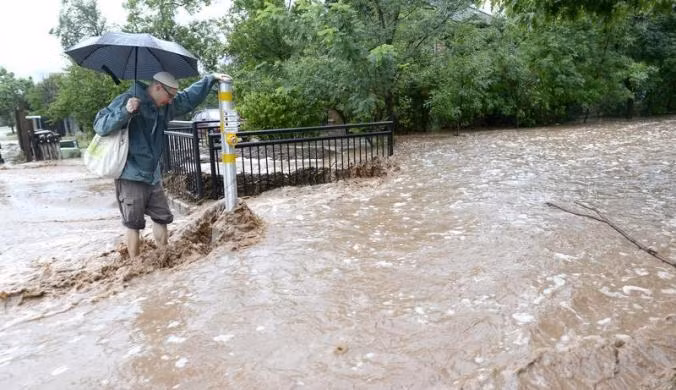 Ông Matthew Messner vất vả di chuyển trên đường phố ngập lụt ở Boulder.