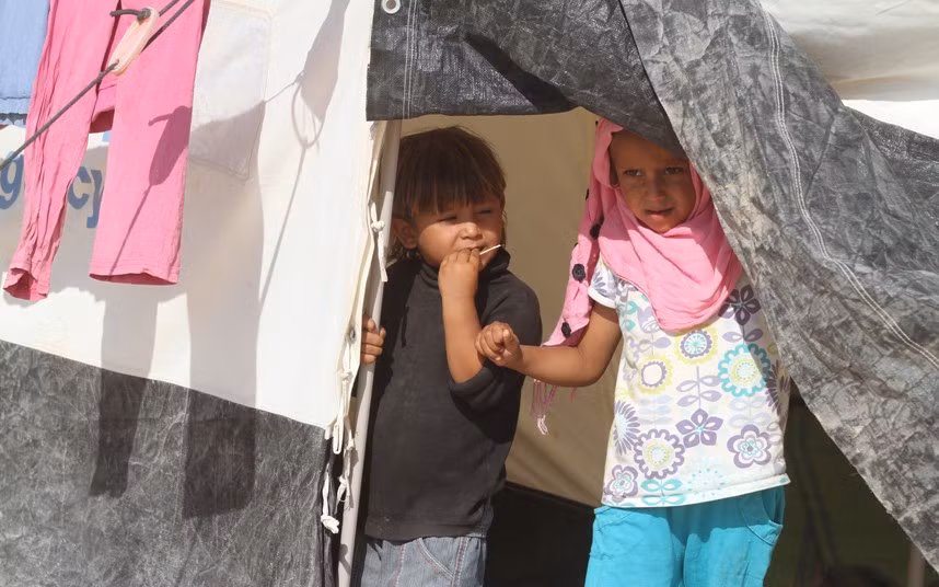 Hai chị em gái đứng trong lều tại trại tị nạn Zaatari.