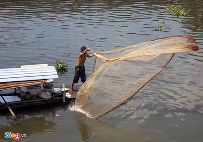 Cuộc sống mưu sinh của những cư dân xóm chài là đánh cá trên sông Sài Gòn và những nhánh sông của nó. Bất cứ ngày, đêm, theo con nước lên xuống, họ chèo thuyền dọc con sông, có khi xa hàng chục km để thả lưới, quăng chài. Công việc hằng ngày của họ gắn liền với những tấm lưới chài. Nỗi lo toan cơm áo, gạo tiền, thuốc thang nhờ cả vào nó. Trong ảnh là anh Nguyễn Ngọc Ái, 47 tuổi, một ngư dân của xóm đang quăng chài bắt cá vào giữa buổi trưa, trước khi nước dâng.