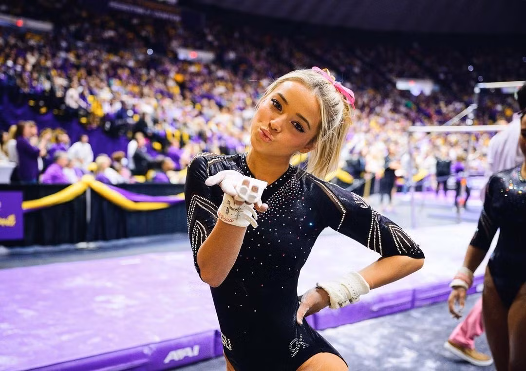 Olivia Dunn (19 tuổi) là sinh viên và VĐV thể dục dụng cụ của Đại học bang Louisiana (LSU). Tháng 6/2021, Hiệp hội Thể thao Đại học Quốc gia Mỹ (NCAA) thay đổi quy tắc NIL, tức cho phép VĐV ở cấp độ đại học kiếm tiền từ tên tuổi và hình ảnh của họ. Nhờ đó, Dunne nhận được nhiều lời mời hấp dẫn từ các nhãn hàng. Theo The New York Post, cô là người có thu nhập cao nhất trong “kỷ nguyên NIL”, có thể lên tới 1 triệu USD vào năm ngoái.