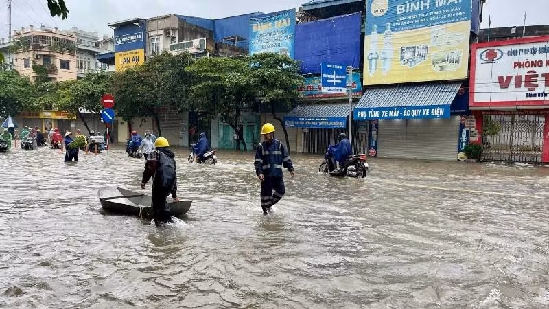 Công nhân ngành điện lực dùng thuyền di chuyển tại ngã tư Trần Hưng Đạo - Hàng Thao (Ảnh: T.K). 