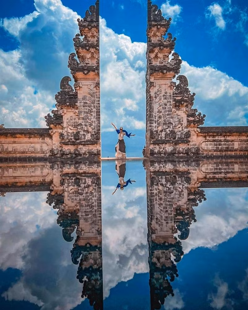 Sau khi đến cổ vũ Minh Khắc thi Man Of The Year, Hương Giang dành những ngày sau đó để đi du lịch. Người đẹp chuyển giới không bỏ lỡ cơ hội check-in tại cổng trời nổi tiếng ở đền Lempuyang nhưng phải khoác thêm khăn vì mặc váy hở lưng. Đền Lempuyang được xem là một trong những ngôi đền cổ kính nhất, mang đậm dấu ấn tôn giáo đặc trưng của Indonesia và cũng là một nơi check-in nổi tiếng nhất Bali. Nơi đây có Heaven’s gate (Cổng Trời) - một địa điểm "sống ảo" được các du khách sẵn hàng chờ đợi hàng giờ đến lượt chụp ảnh.