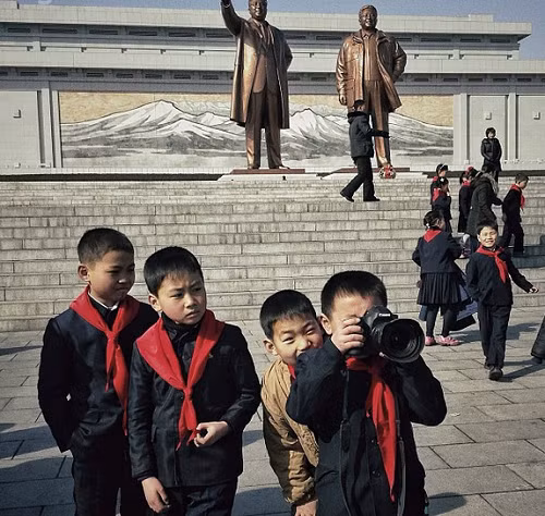 Trẻ em vui đùa dưới tượng đài hai cựu lãnh tụ Kim Nhật Thành và Kim Jong Il.
