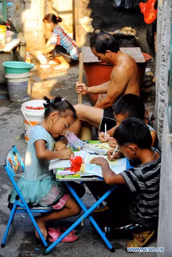 Bé gái Pan Simei, 7 tuổi và 2 bạn học ở làng Baisha thành phố Liuzhou, chung nhau một chiếc bàn nhỏ. 2 bé trai thậm chí còn không có ghế ngồi.