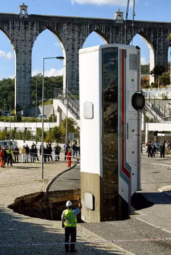 Cứu hộ kéo chiếc xe bus khỏi hố tử thần bất ngờ xuất hiện trên đường phố Lisbon ngày 25/10/2003.