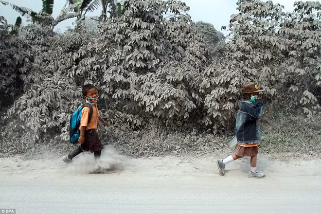 Hai em bé trên đường đi học khi khung cảnh xung quanh nhuốm tro bụi. Ảnh: EPA.