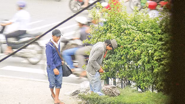 Người nghiện ngang nhiên tiêm chích ở chốn đông người (dải phân cách trên quốc lộ 22 đoạn gần ngã tư Trung Chánh, Q.12, TP.HCM).