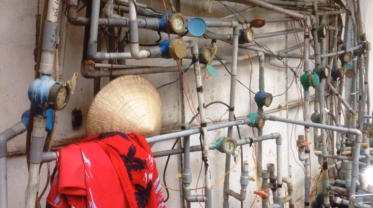 Hệ thống ống cấp nước sinh hoạt trong khu đất vàng lộn xộn, chằng chịt và cũ kỹ.