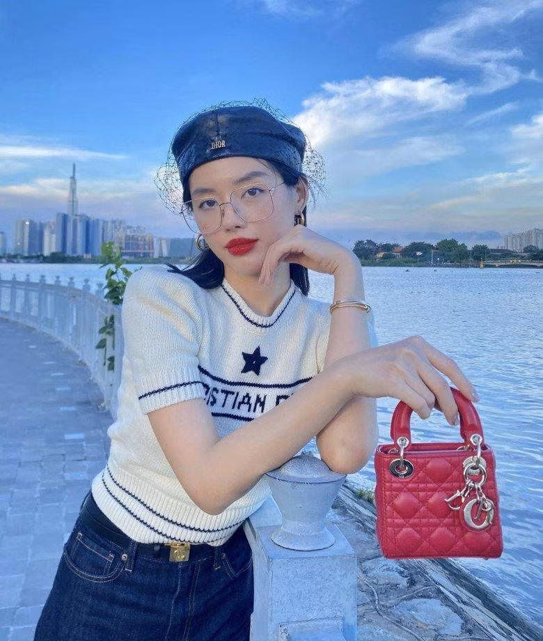 "Cô Em Trendy" Khánh Linh cổ điển hơn khi kết hợp thêm phụ kiện mũ nồi Dior và túi Lady Dior màu đỏ làm điểm nhấn cho outfit thêm mãn nhãn.